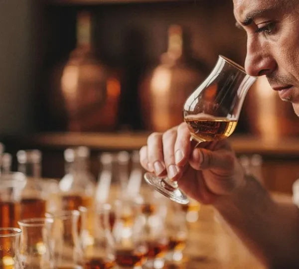 Master blender examining whisky samples in a quiet blending room surrounded by test tubes and beakers