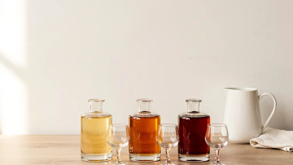 A minimalist arrangement of three small glass carafes filled with spirits of varying amber tones on a clean wooden board, ready for a tasting flight