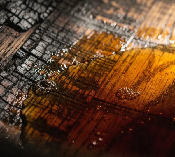 Close-up view of charred oak barrel interior showing wood grain texture and golden whiskey reflections