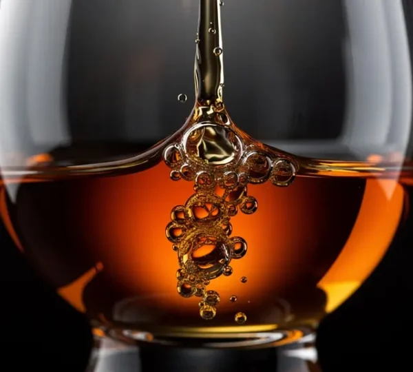 Close-up view of whisky forming legs in a crystal nosing glass with dramatic backlighting