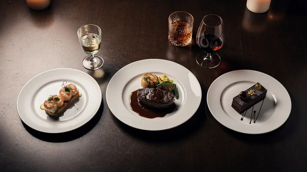 Elegant three-course dinner table set with spirit glasses and food pairings in warm lighting