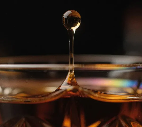 Microscopic view of water droplet meeting whisky surface revealing molecular interactions