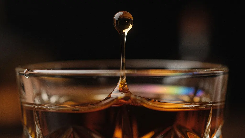 Microscopic view of water droplet meeting whisky surface revealing molecular interactions